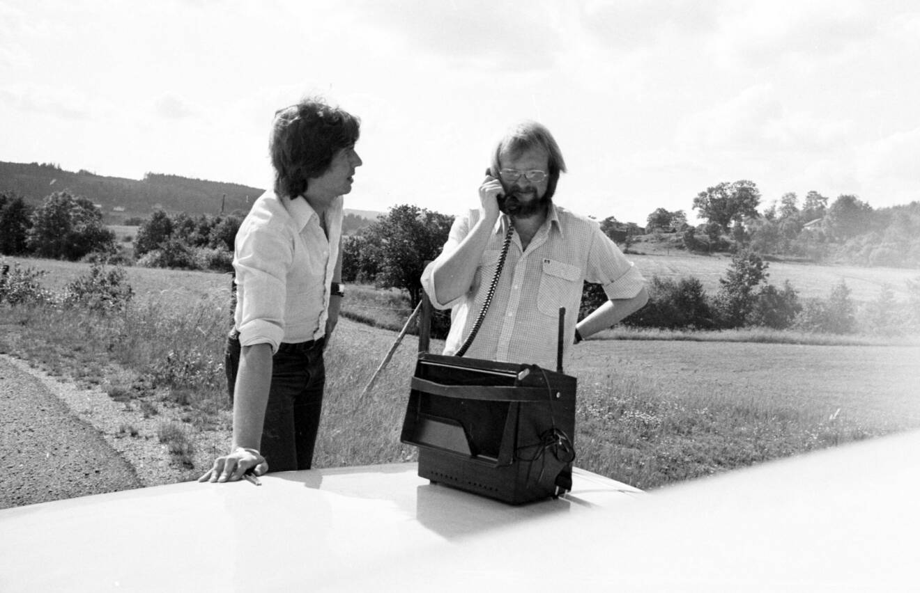 två män samtalar i en stor låda till telefon