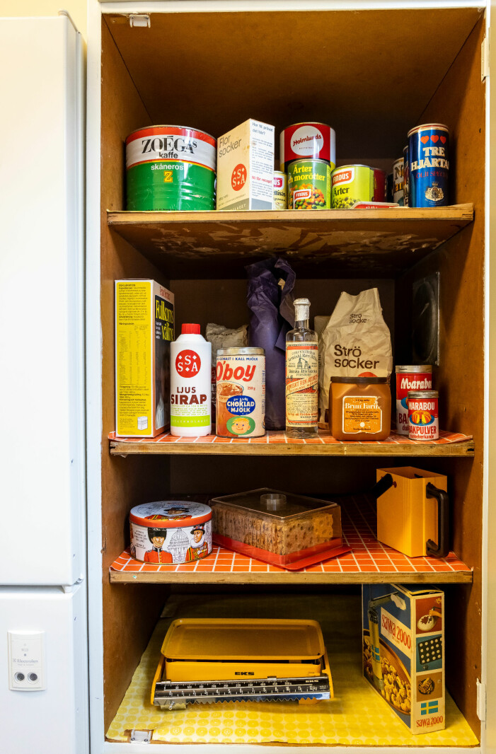 Det var svårt att få tag på förbrukningsvaror till köket, då dessa ofta kastas när bäst före-datumet passerat. Skafferi med öppna hyllor fyllda med förpackningar av varor som var vanliga på 70-talet. Här finns bland annat en kaffeburk från Zoega, en burk bakpulver, en sirapsflaska och en ölburk.