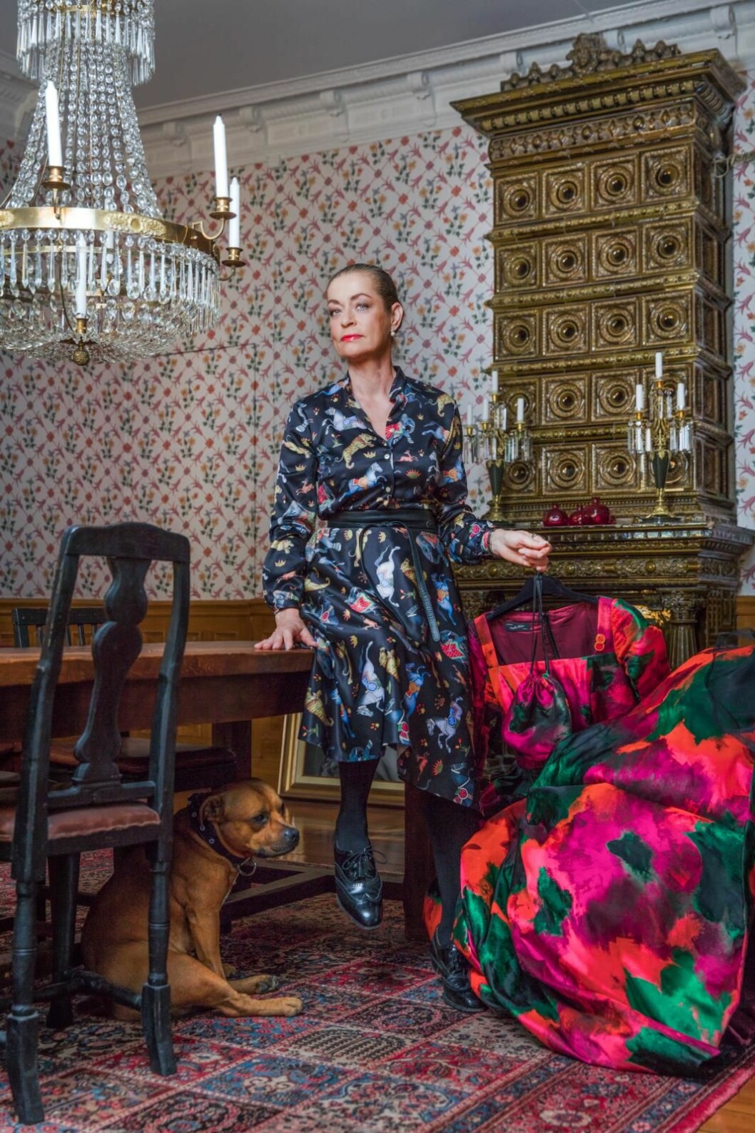 Camilla Thulin har på sig blus och kjol som tillsammans ser ut som en <a href="https://camillathulin.se/">klänning, stl 34–48, 1 599 kr och 1 999 kr, Camilla Thulin.</a> (Under bordet: Musse) Camilla Thulin sitter på ett bord och håller i en klänning med hunden Musse under bordet