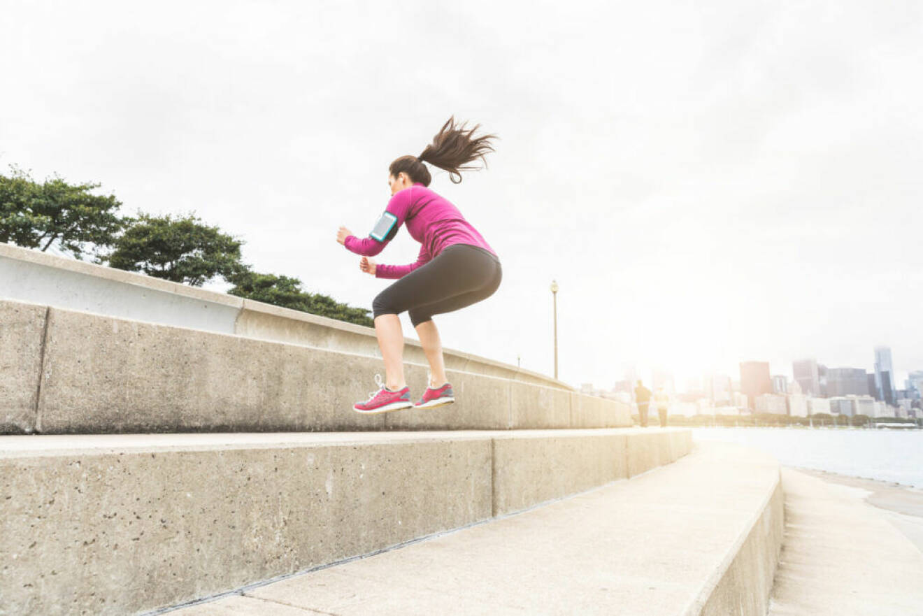 Kvinna gör squat jumps uppför trappa.