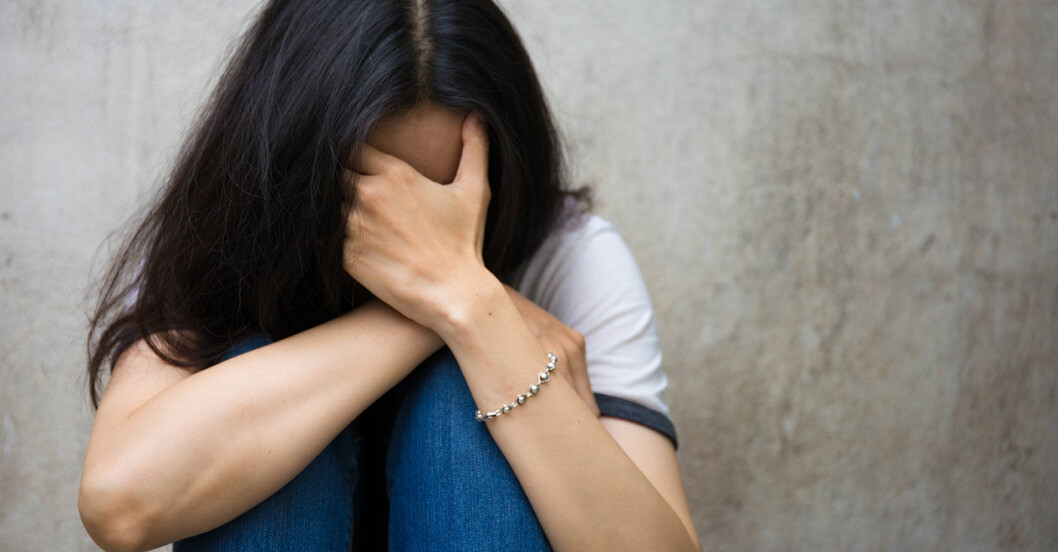 Kvinna med ångest lutar huvudet i händerna