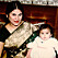Kvinna med indiskt utseende i sari, med liten bebis i knät