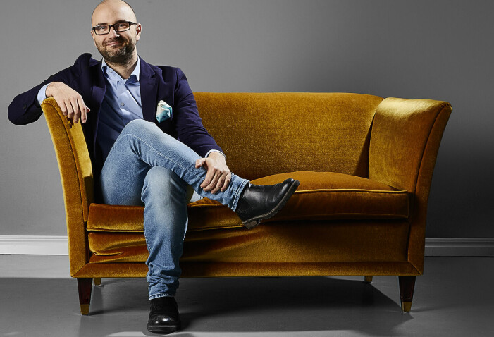 Jani Andersson är antikexpert och vd för Metropol auktioner.<br class=""><span class=" italic" data-lab-italic_desktop="italic">Foto: Metropol auktioner.</span><br class=""> Jani Andersson sitter i en brun soffa och tittar in i kameran och ler.