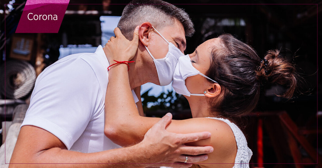 man och kvinna kysser varandra iförda ansiktsmasker