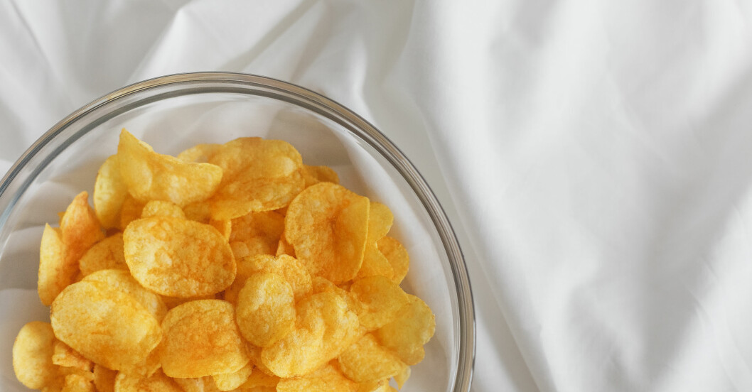 En glasskål med chips står på ett vitt lakan.