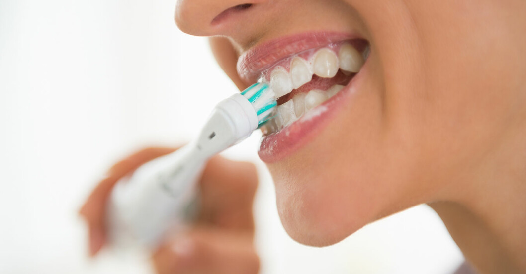 Eltandborste kvinna med öppen mun borstar tänderna