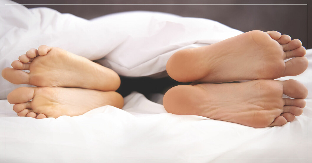 Fötter som är vända från varandra i en säng.