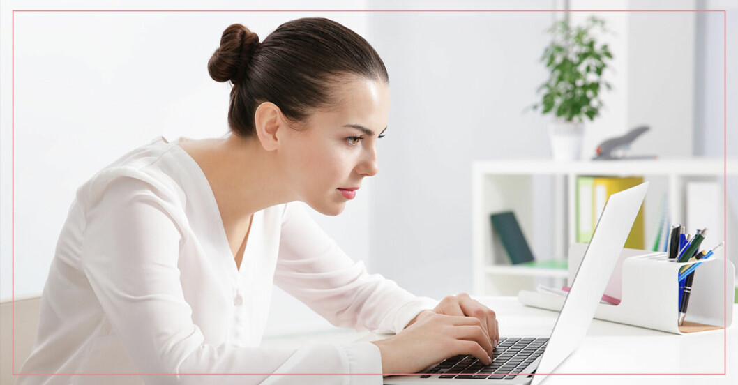 Kvinna med gamnacke sitter framåtlutad vid datorn