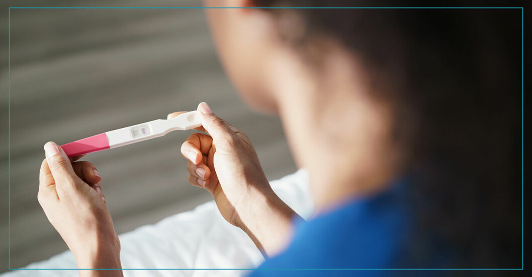 Kvinna tittar på graviditetstest som hon håller i handen