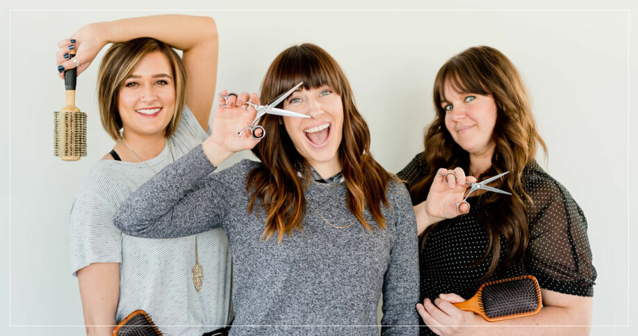 Tre kvinnor som håller i hårborstar och frisörsaxar