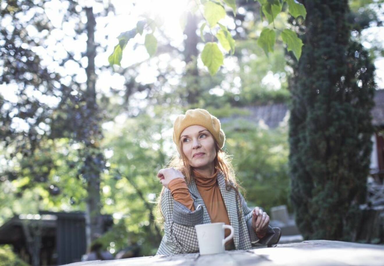 Pia Johansson sittter utomhus med en kaffemugg framför sig. 