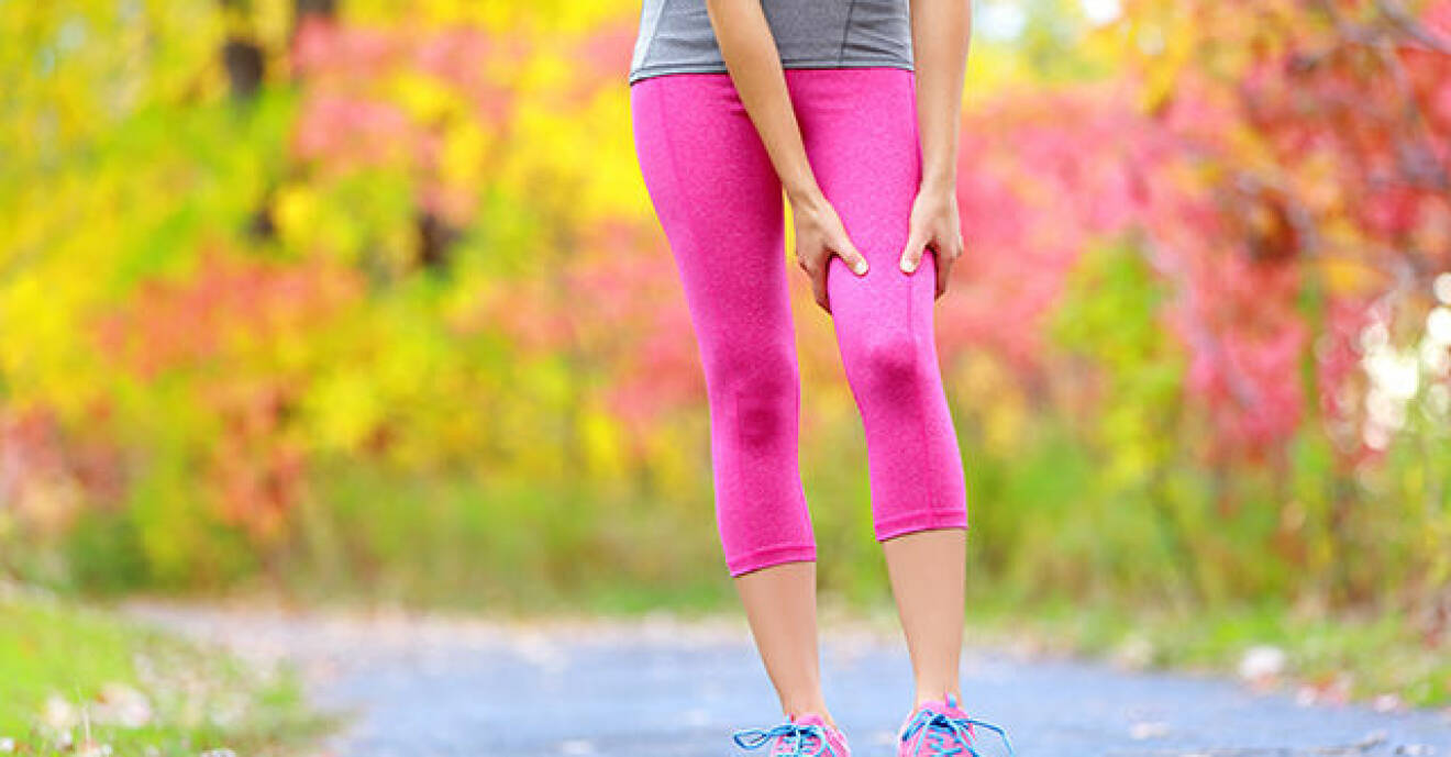 Kvinna i rosa tights har ont i benet.