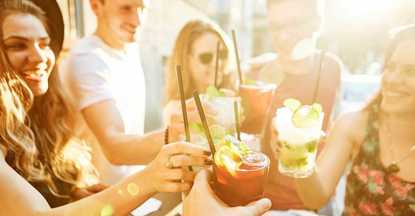 Grupp människor som skålar och dricker drinkar i solen
