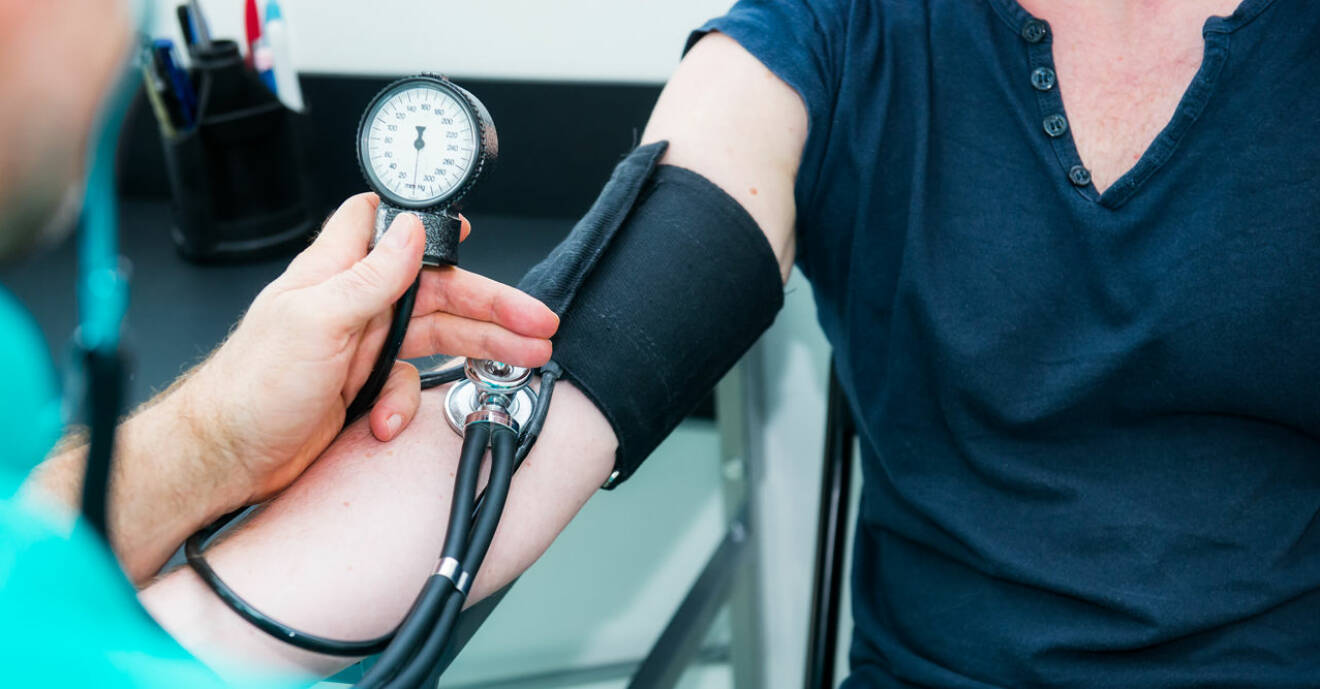 Doktor mäter blodtrycket på en kvinnas överarm