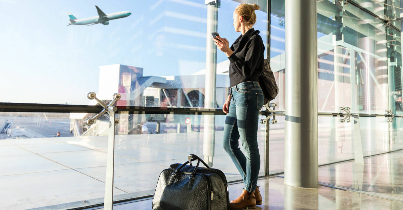 Kvinna står på flygplats ochtittar ut på ett plan som lyfter