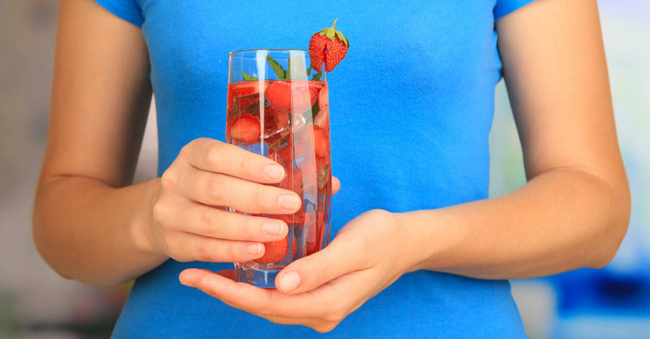 Kvinna som håller en fruktdryck med jordgubbar i sina händer