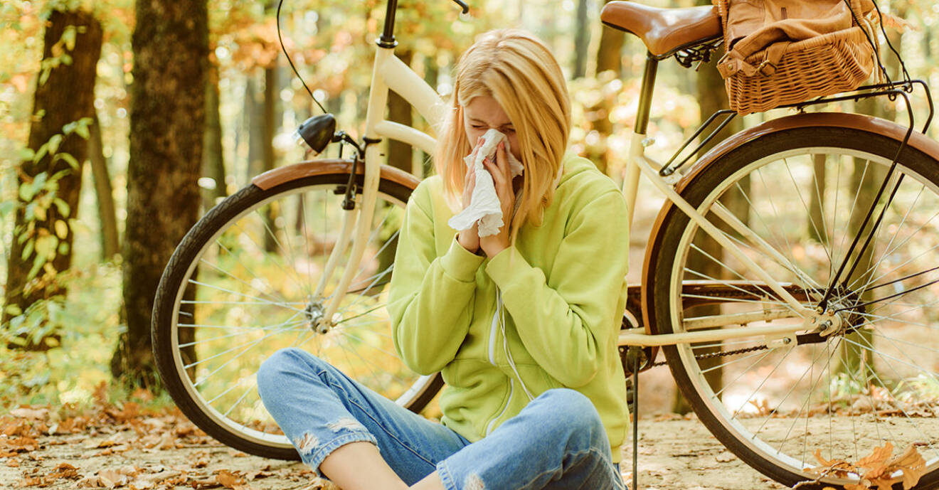 Kvinna sitter ner i naturen och snyter ut pollen ur näsan