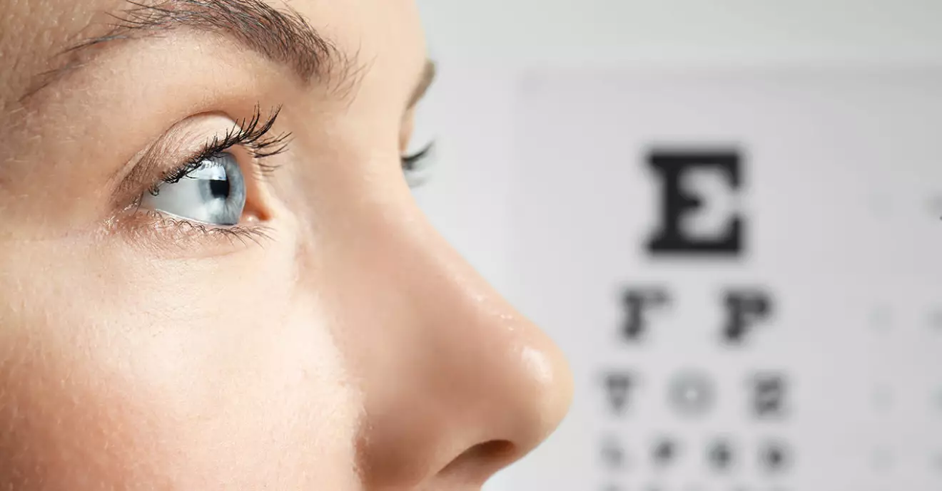 Kvinna med öppet öga, en optikertavla med bokstäver i bakgrunden
