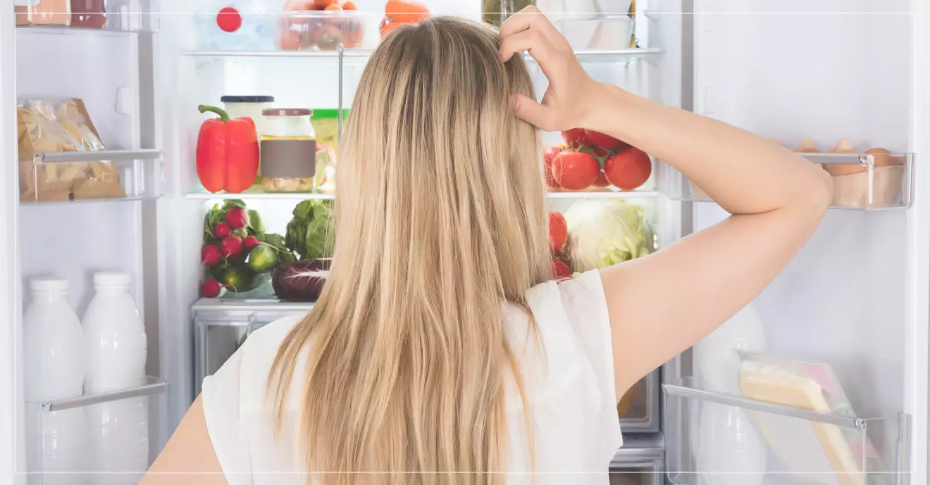 hungrig kvinna letar mat i kylskåpet