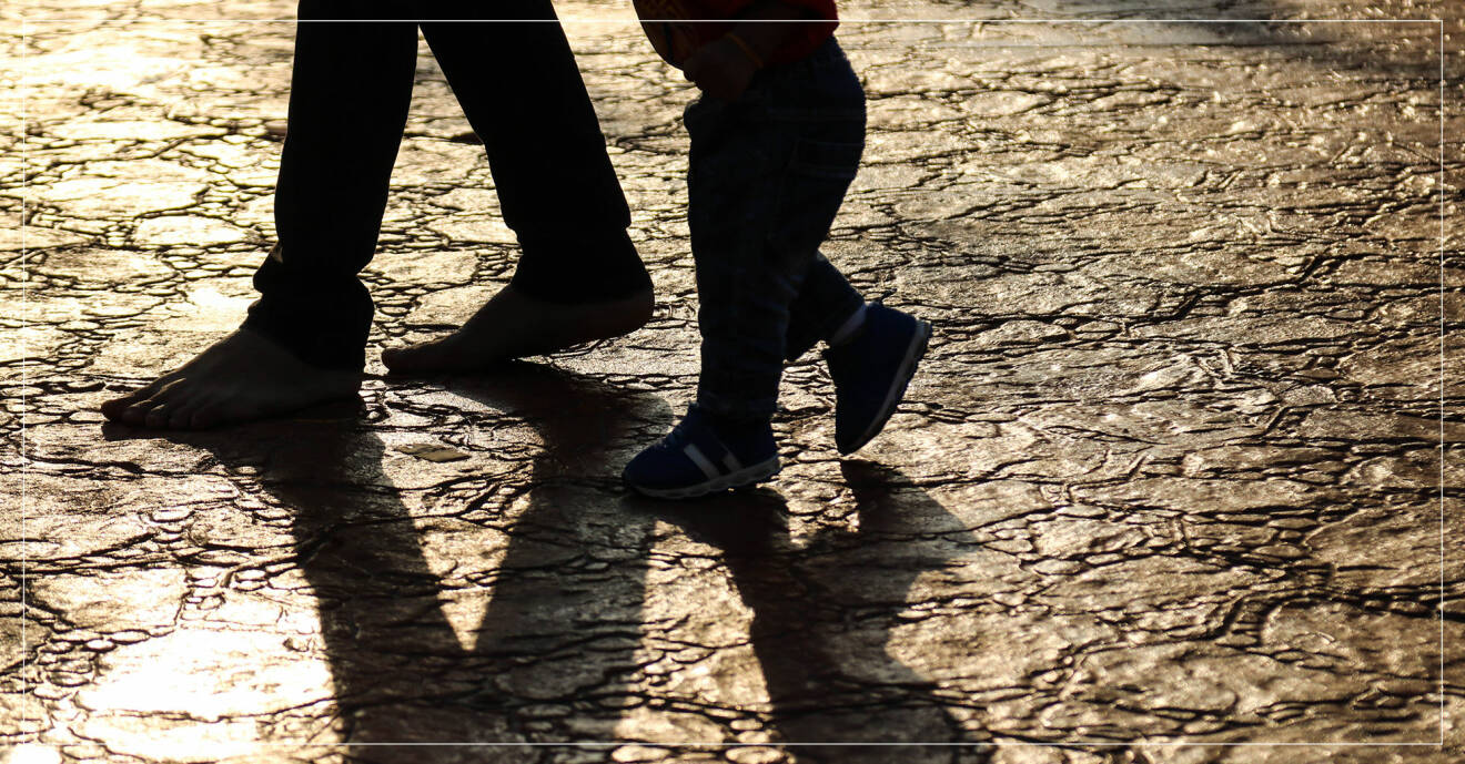 pappa och barn som går tillsammans, fötterna som skuggar marken.