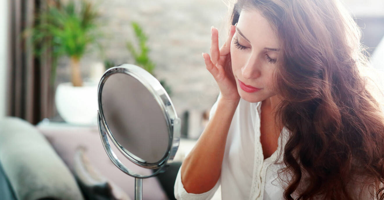Kvinna tittar sig själv i spegeln och vill ha mindre porer.
