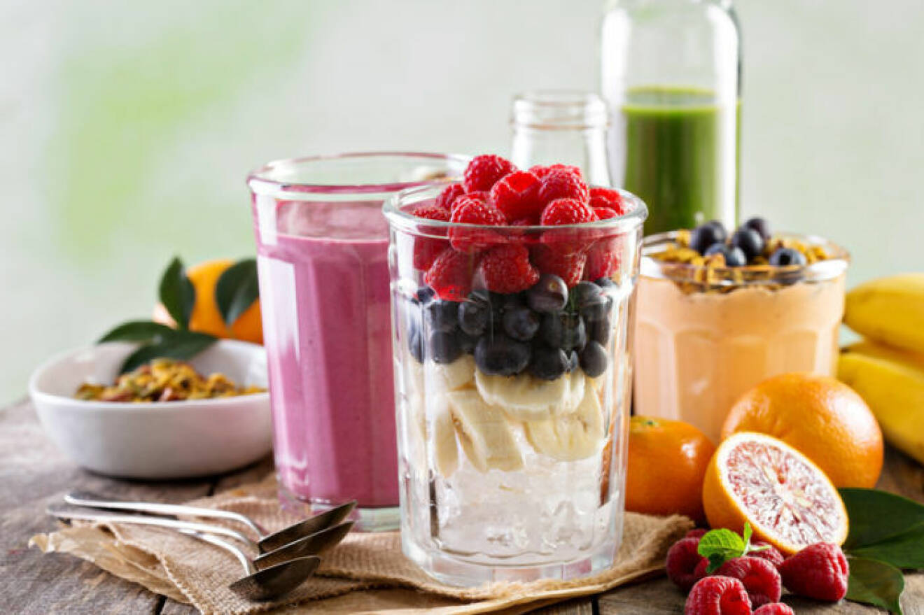 Ingredienser för smoothie i ett glas – banan, blåbär och hallon.