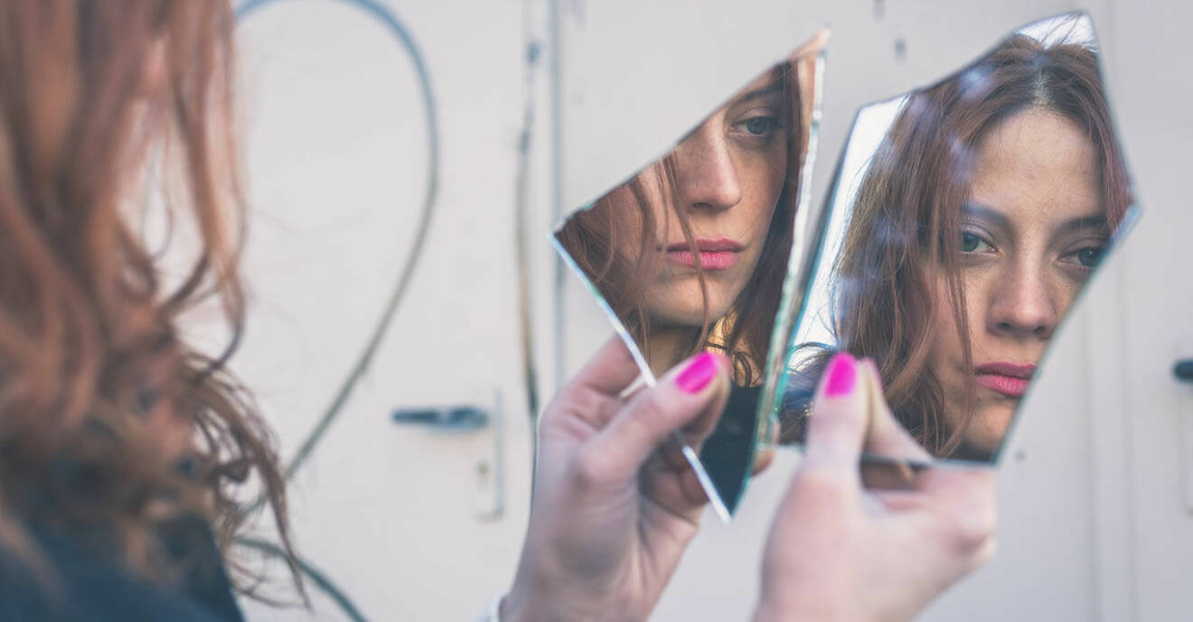 kvinna som haft sönder spegel och tittar i skärvorna