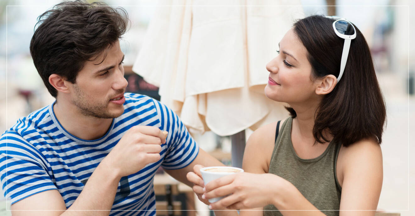 Ung man och kvinna med kaffekopp i handen sitter utomhus och pratar.