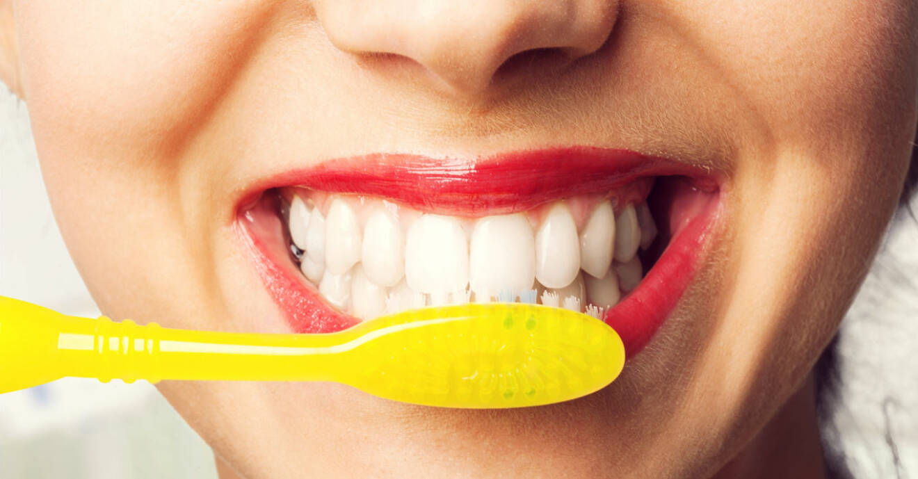 Kvinnas leende mun med gul tandborste.