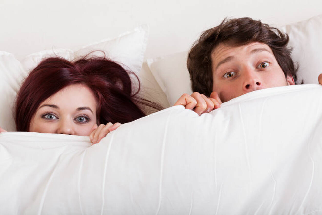 Young attractive couple are surprised in bed together