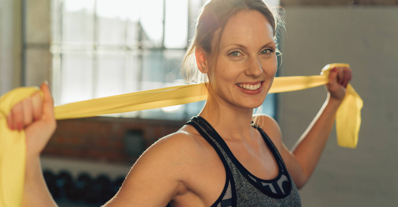 Kvinna tränar med gummiband som är vanligt vid rehabträning