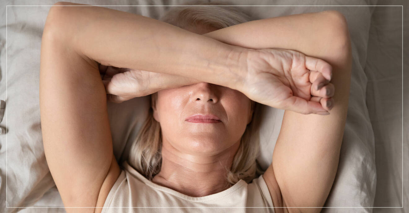 kvinna ligger i säng och täcker över ögonen på grund av huvudvärk