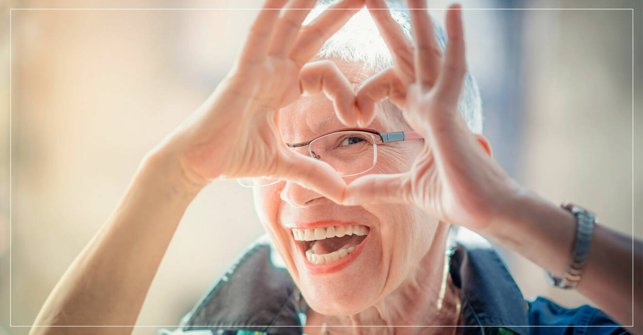 äldre kvinna gör ett hjärta med fingrarna.