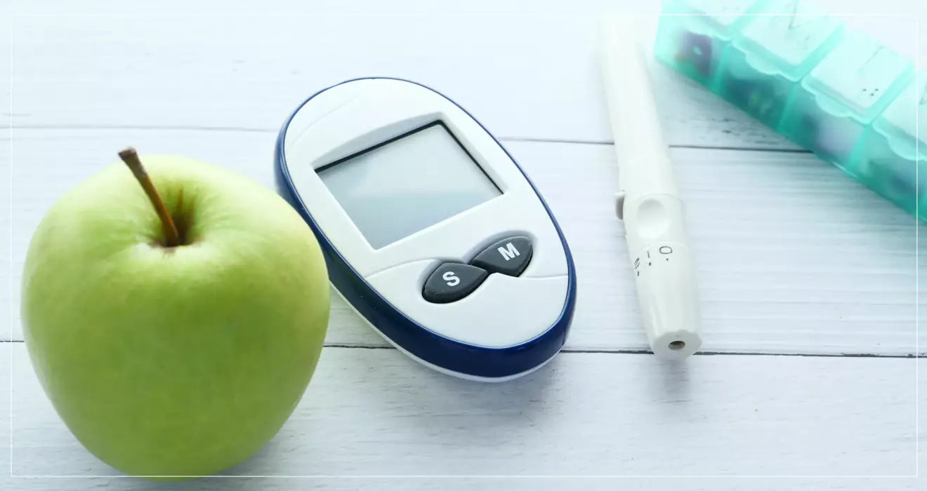 Glukosmätare, grönt äpple, insulinspruta och diabetesmedicin.