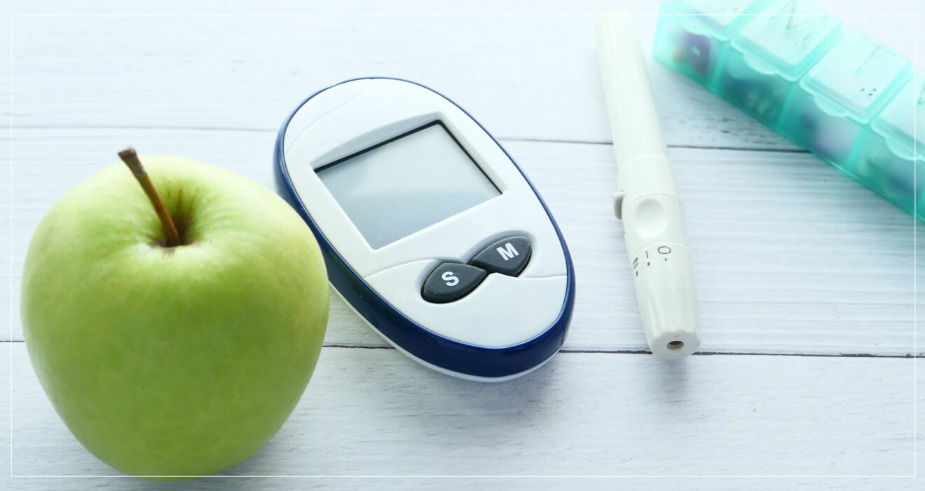 Glukosmätare, grönt äpple, insulinspruta och diabetesmedicin.