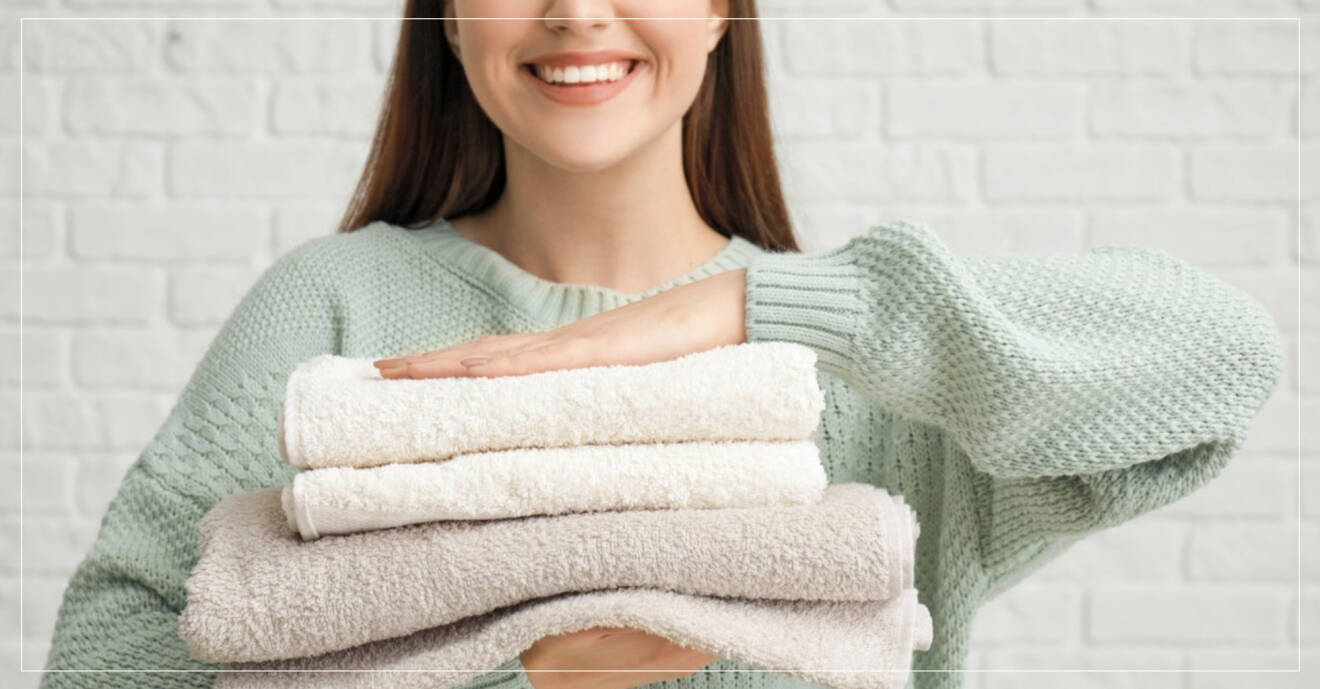 kvinna som håller en hög med nytvättade handdukar