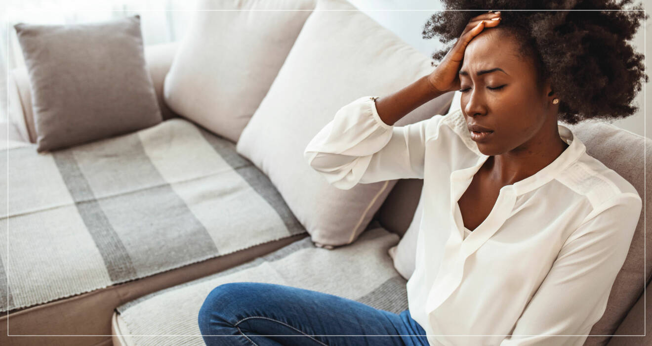 Kvinna i soffa med huvudvärk på grund av östrogenbrist.