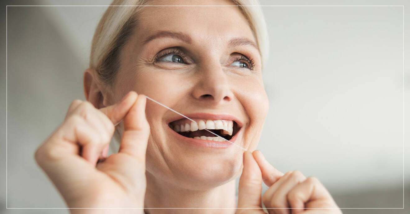 Kvinna gör rent mellan tänderna med tandtråd