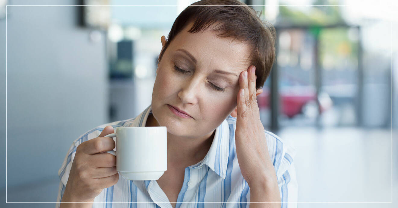 Kvinna med huvudvärk som dricker kaffe.
