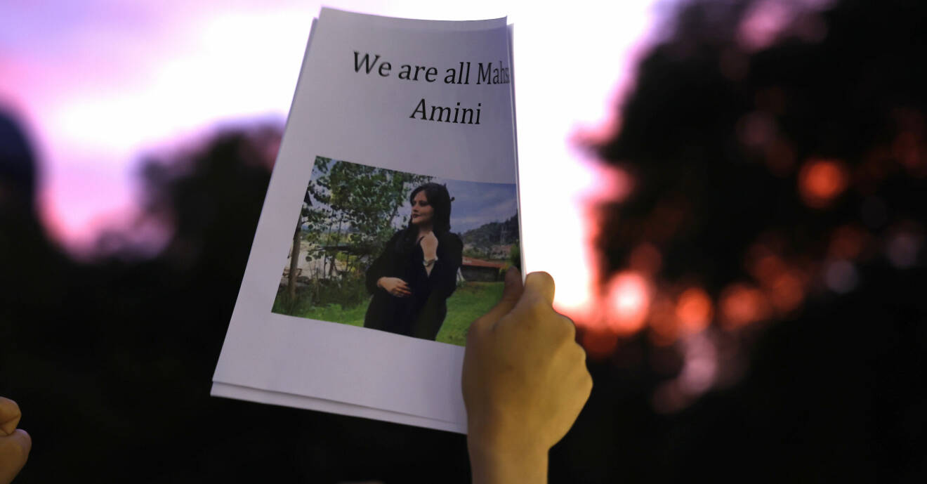 Person håller upp lapp med bild på Masha Amini med texten ”We are all Masha Amini”
