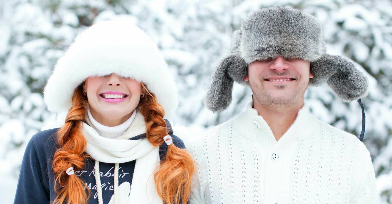 Ungt par står ute i snön och ler.