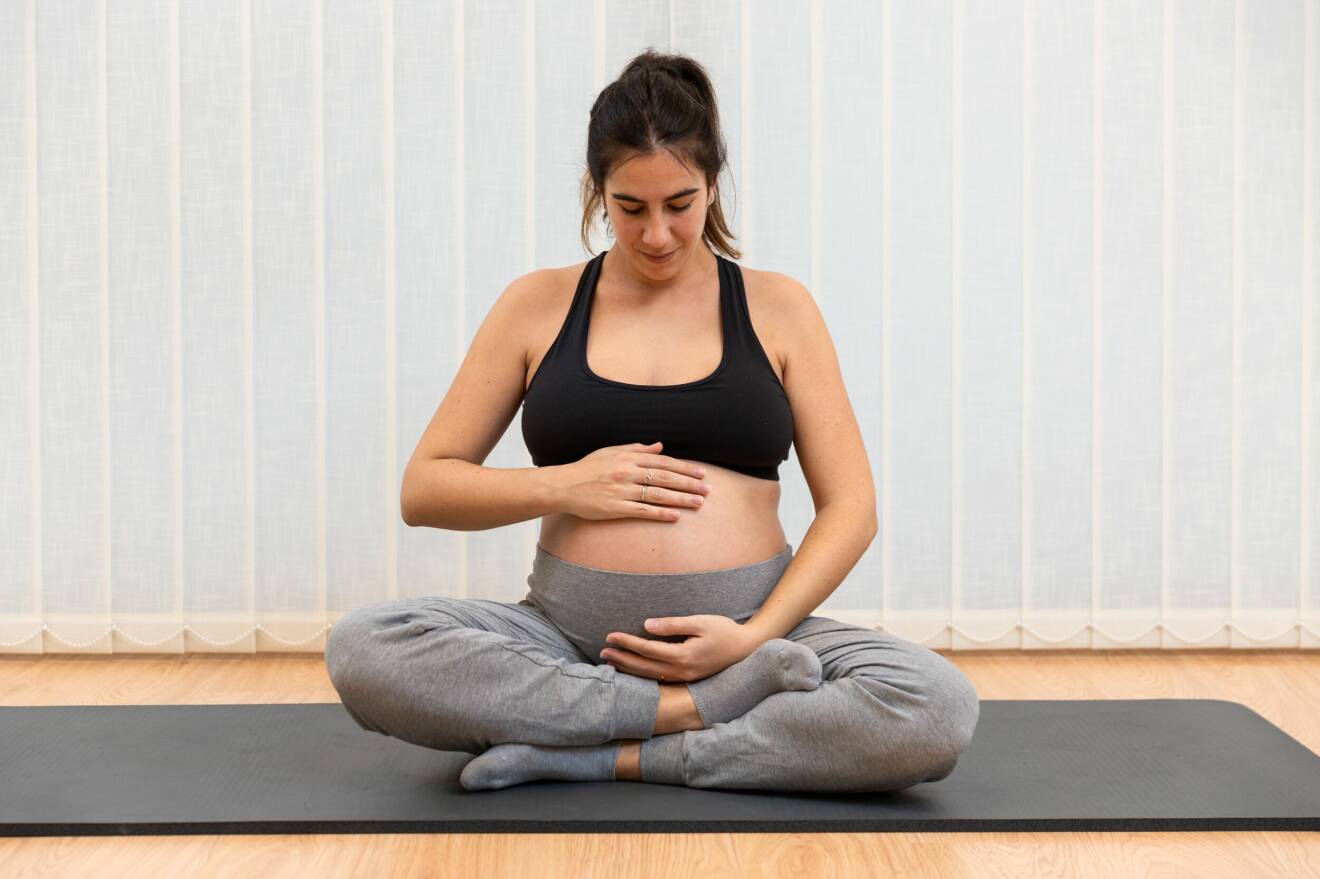 En gravid kvinna som sitter på golvet.