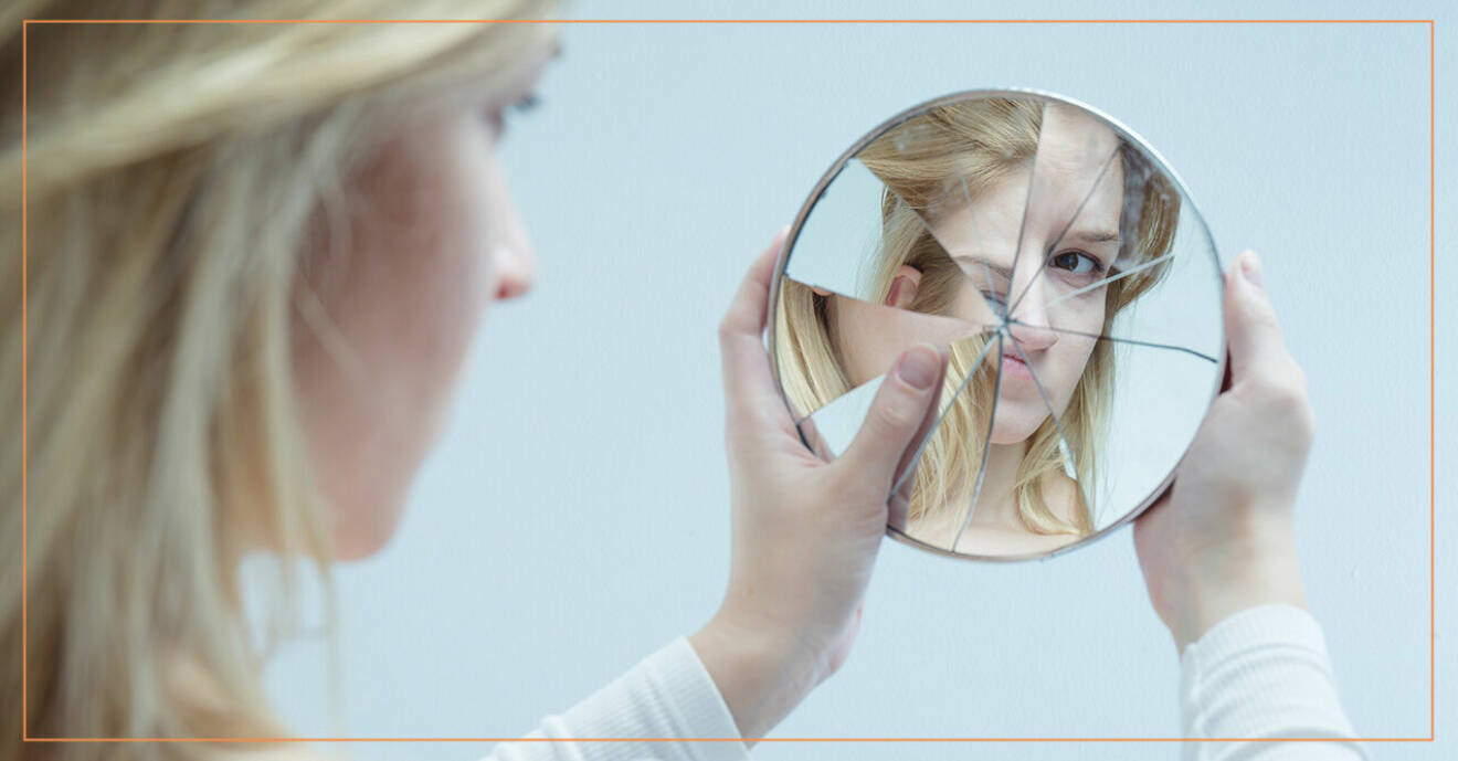 Kvinna tittar på sig själv i en trasig spegel