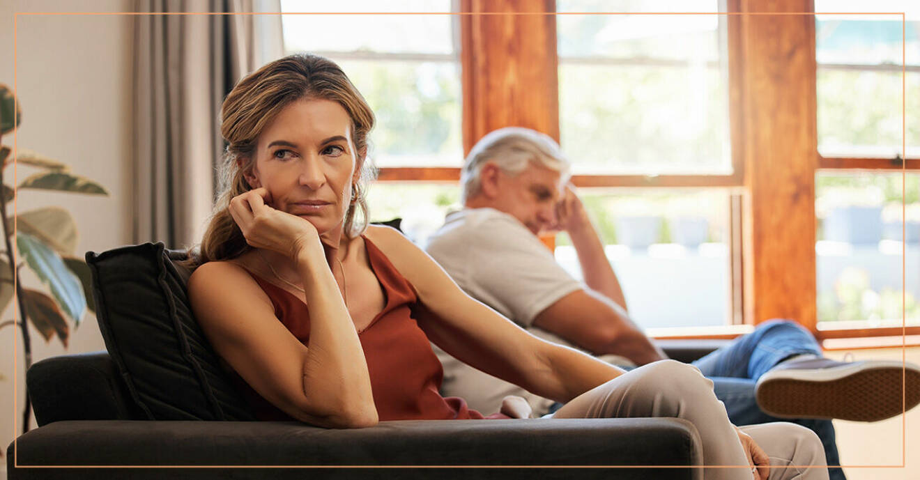 Missnöjd kvinna sitter bredvid sin make i soffan