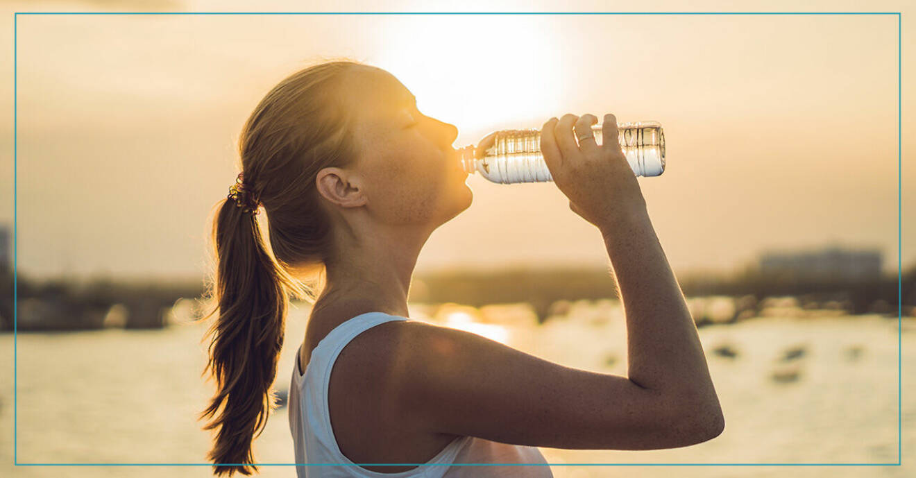 Kvinna dricker vatten på stranden i solnedgången