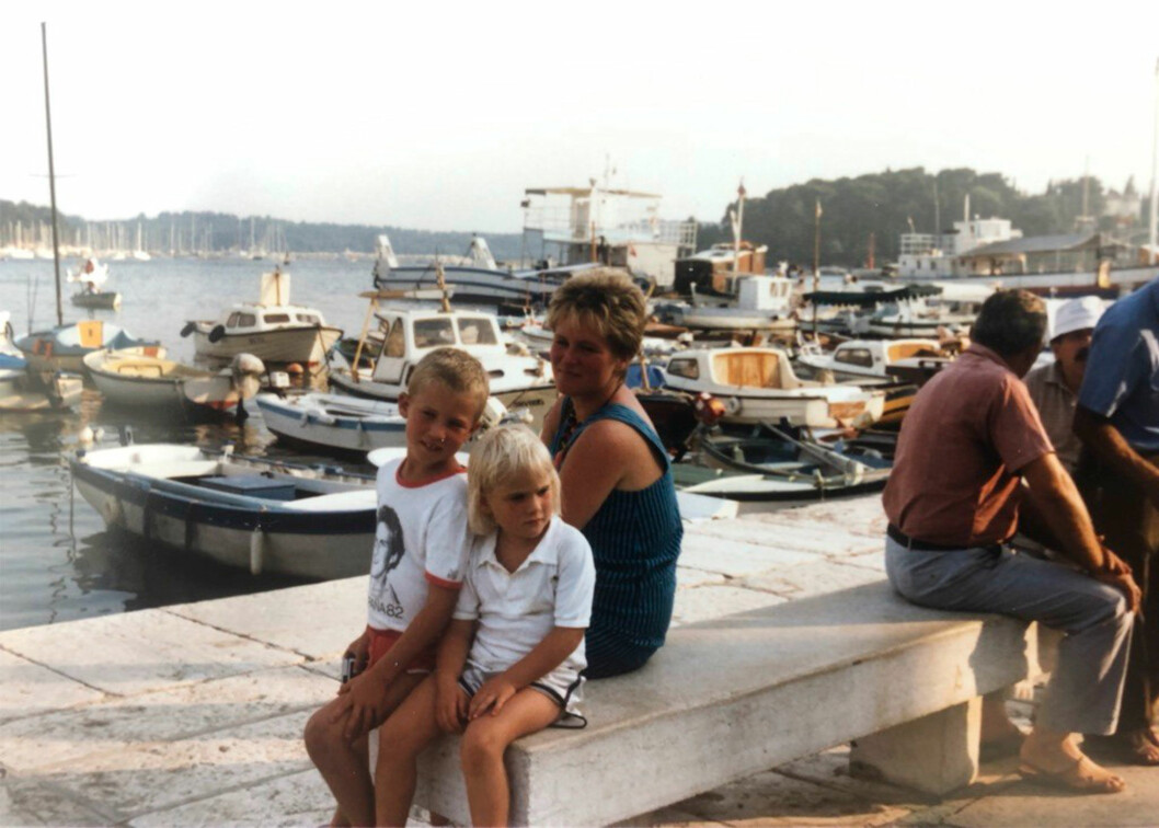Lisa har fina barndomsminnen från husvagnssemestrarna med familjen. Foto: Privat Kocken Lisa Lemke som barn sitter på en kaj utomlands med sin bror och mamma.