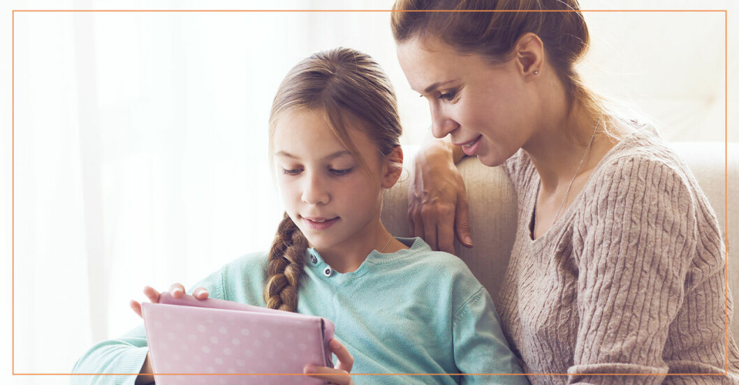En kvinna som sitter med sin dotter och tittar på en ipad