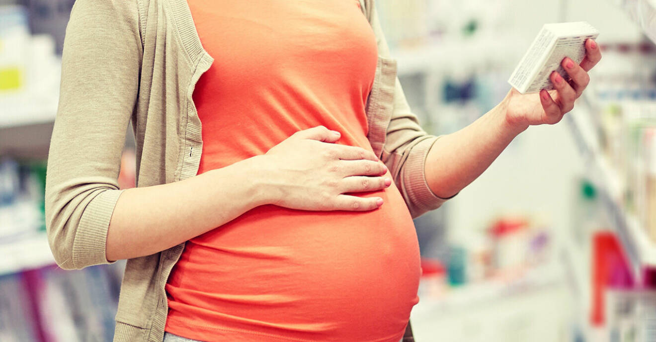 Gravid kvinna som betraktar ett läkemedel.