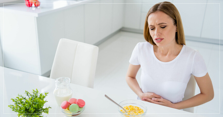 kvinna håller för magen och ser ut att ha ont i samband med måltid
