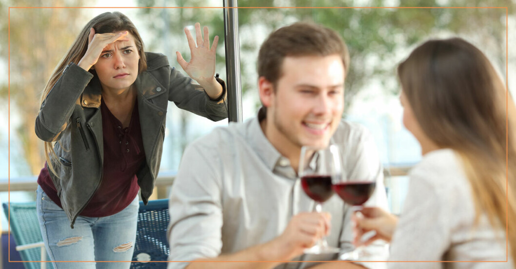En kvinna som kikar in genom ett fönster där en man dricker vin med en kvinna